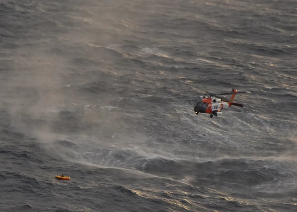 U.S. Coast Guard MH-60 Jayhawk helicopter hovering over rough ocean during a rescue operation